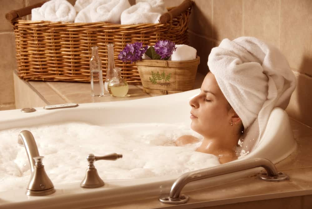 a girl with a towel on her head in a bath enjoying spa time