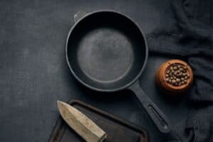 Cast iron skillet with knife and bowl of peppercorn