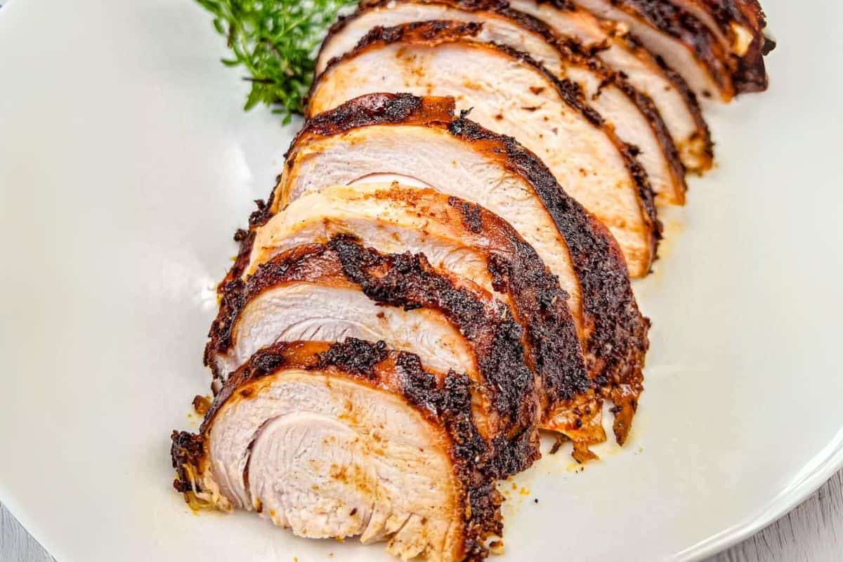 Sliced roasted turkey breast arranged on a white plate.